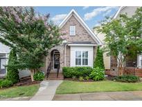 Charming brick home featuring a manicured front yard with flowering trees, a stone archway and welcoming front door at 43 Salt Cedar Ln, Chapel Hill, NC 27516