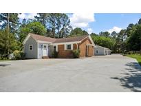 Charming single-story home featuring a brick facade, white trim, and an expansive driveway surrounded by mature trees at 5820 Wake Forest Hwy, Durham, NC 27703