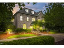 Charming brick home with manicured landscaping, illuminated by exterior lighting at dusk at 6005 Carlyle Dr, Raleigh, NC 27614