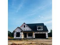 New construction home with a black roof and wrapped in white material, set on a dirt lot under a bright blue sky at 6332 River Rd, Fuquay Varina, NC 27526