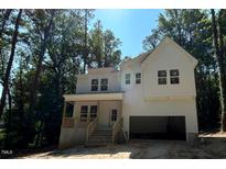 New two-story white home boasts an attached garage, covered porch with wooden railing and surrounded by mature trees at 701 Locust Ln, Raleigh, NC 27603