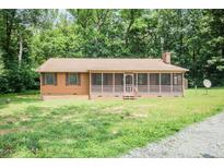 Ranch-style home with wood siding and a screened front porch, nestled in a wooded area at 7030 Stockard Rd, Snow Camp, NC 27349