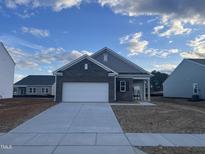 New construction home with a gray brick facade, a two car garage, and a concrete driveway at 724 Shepard Rock Dr, Zebulon, NC 27597