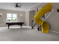 Spacious carpeted basement featuring a pool table and a bright yellow slide leading from the upper level at 7409 Chesley Ln, Durham, NC 27713