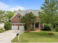 Charming brick home boasts a well-manicured lawn, mature trees, and attached two-car garage at 7409 Chesley Ln, Durham, NC 27713