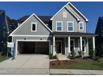 Charming two-story home with gray siding, covered porch, and attached two-car garage at 747 Bachelor Gulch Way, Apex, NC 27523