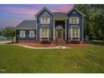 Charming blue two-story home boasts a landscaped front yard, brick foundation, and inviting entrance at 104 Goldleaf Ct, Angier, NC 27501
