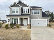 Charming two-story home with gray siding, black shutters, covered porch, and two-car garage at 13 Knotty Pine Lane, Clayton, NC 27520