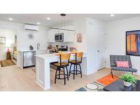 Modern kitchen with stainless steel appliances, a breakfast bar, and sleek white cabinetry in a bright open-concept space at 1309 Hudson Ave # D16, Durham, NC 27705