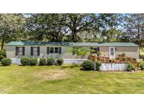 Inviting home with a green metal roof, manicured landscaping, and charming wood deck and railing at 1355 Sykes Rd, Spring Hope, NC 27882
