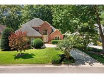 Charming brick home featuring mature trees, lush green lawn and a circular driveway at 200 Greensview Dr, Cary, NC 27518