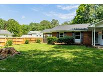 Well-manicured lawn and a charming brick exterior with dark shutters create curb appeal in this backyard at 2821 Regent Park Ln, Burlington, NC 27217