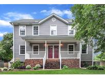 Charming two-story home features a welcoming front porch and well-manicured lawn and red double front doors at 8121 Bentwood Pl, Raleigh, NC 27615