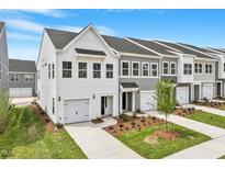 New construction townhomes show crisp white siding and an attached garage, complemented by a well manicured lawn at 123 Central Townes Way # 302, Raleigh, NC 27603