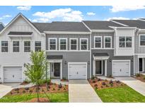 Charming townhomes featuring attached garages, sidewalks, and well maintained landscaping on a sunny day at 127 Central Townes Way # 303, Raleigh, NC 27603
