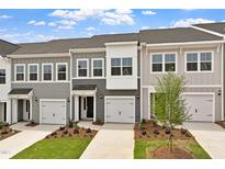 Charming townhomes featuring varied siding and attached garages under a partly cloudy, bright blue sky at 131 Central Townes Way # 304, Raleigh, NC 27603