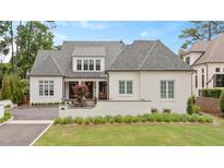 Charming two-story home with white brick, gray roof, manicured lawn and front yard garden at 1312 Duplin Rd, Raleigh, NC 27607