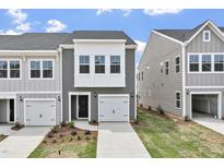 New two-story townhouse showcasing a white garage door, black front door, and landscaped front yard at 139 Central Townes Way # 306, Raleigh, NC 27603