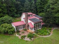 Aerial view of a charming home boasting a red roof and beautiful landscaping at 145 Ryan Rd, Pittsboro, NC 27312