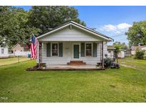 Charming bungalow features a well-manicured lawn, American flag, and a welcoming front porch at 303 N Watauga Ave, Dunn, NC 28334