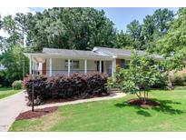 Charming home with white exterior, brick accents, covered porch, and manicured landscaping at 325 Northfield Dr, Raleigh, NC 27609