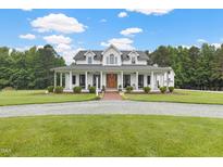 Stunning two-story white home featuring a charming wrap-around porch and a meticulously landscaped front yard at 4737 Uzzle Rd, Rougemont, NC 27572