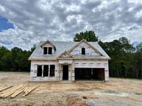New home construction featuring a two-story design, open garage, and timbered lumber in a partly cloudy setting at 477 Beacon Hill Rd # 29, Lillington, NC 27546
