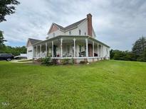 Charming farmhouse with a large wraparound porch and lush green lawn at 526 Bob Rainey Trl, Burlington, NC 27217