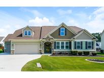 Inviting two-story home featuring a well-manicured lawn and a two-car garage with stone detailing at 67 Bornean Dr, Garner, NC 27529
