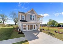Charming two-story home featuring a covered porch and gray siding, complemented by a well-manicured lawn at 1305 Westerland Way # 17, Durham, NC 27703