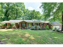 Charming brick home featuring a well-manicured lawn, mature trees, and a welcoming front porch, enhancing its curb appeal at 1416 Bramble Dr, Durham, NC 27712