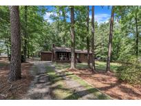 Charming brick home with a cozy front porch, surrounded by mature trees and natural landscaping at 2005 Messer Rd, Raleigh, NC 27603