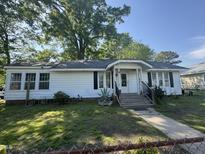 Charming single-story home featuring a well-maintained yard, cozy porch, and lovely curb appeal on a sunny day at 212 S Sixth St, Smithfield, NC 27577