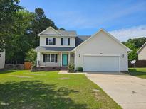 Charming two-story home featuring a well-manicured lawn, attached garage, and inviting turquoise-colored front door at 216 Edgecombe Dr, Spring Lake, NC 28390