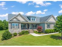 Charming home with stone accents, lush landscaping, and a covered front porch, perfect for enjoying the outdoors at 216 Tarkenton Ct, Clayton, NC 27527