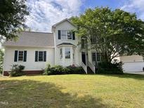 Charming white two-story home with green shutters and a well-manicured lawn on a sunny day at 2208 Fieldmont Ct, Raleigh, NC 27614