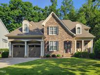Charming stone and siding home featuring a two-car garage and a well-manicured lawn at 224 Midden Way, Holly Springs, NC 27540