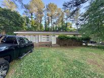 Single story brick home on a lot with sparse grass and various shrubs and trees at 603 Pineland St, Sanford, NC 27330