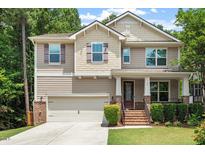 Charming two-story home featuring tan siding, brick accents, a well-manicured lawn, and an attached two-car garage at 724 Piermont Dr, Cary, NC 27519