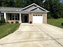 Charming single-story home with a brick facade, white garage door, and well-maintained landscaping at 820 Houston Ct, Haw River, NC 27258