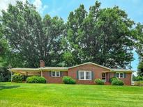 Charming brick home with lush green lawn and mature trees providing shade and curb appeal at 9455 Boston Rd, Roxboro, NC 27574