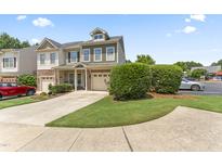 Inviting townhome featuring a manicured lawn, attached garage, and charming curb appeal at 100 Beaconwood Ln, Holly Springs, NC 27540