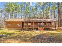 Charming log cabin with a cozy front porch, nestled amongst a backdrop of tall pine trees at 1101 Dimmocks Mill Rd, Hillsborough, NC 27278