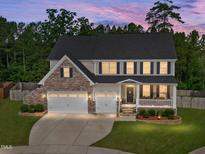 Two-story home with stone accents, a charming front porch with swing, a manicured lawn and a two-car garage at 232 Randleman Ct, Holly Springs, NC 27540