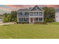 Charming two-story home with a manicured lawn, double porches, and a striking red front door at 470 E Wellesley Dr, Clayton, NC 27520
