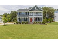 Charming two-story home with a spacious lawn, double porches, and an eye-catching red front door at 470 E Wellesley Dr, Clayton, NC 27520