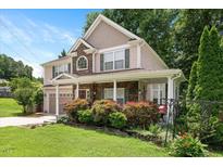 Charming two-story home with stone accents, covered porch, manicured lawn and lush landscaping at 517 Wheddon Cross Way, Wake Forest, NC 27587