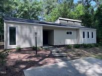Modern home with horizontal siding, dark roof, and small concrete walkway leading to the covered front entrance at 5228 Olive Rd, Raleigh, NC 27606
