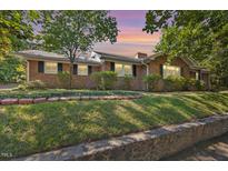 Charming single-story brick home featuring a landscaped front yard and beautiful sunset in the background at 800 Camden Ave, Durham, NC 27701