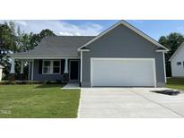 Charming one-story home featuring a two-car garage, and a well-manicured lawn at 140 Oakfield Trace Dr, Four Oaks, NC 27524